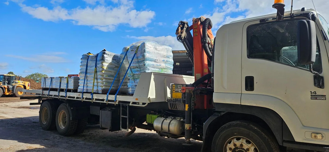 Hiab truck loaded with bagged landscape supplies and pavers.