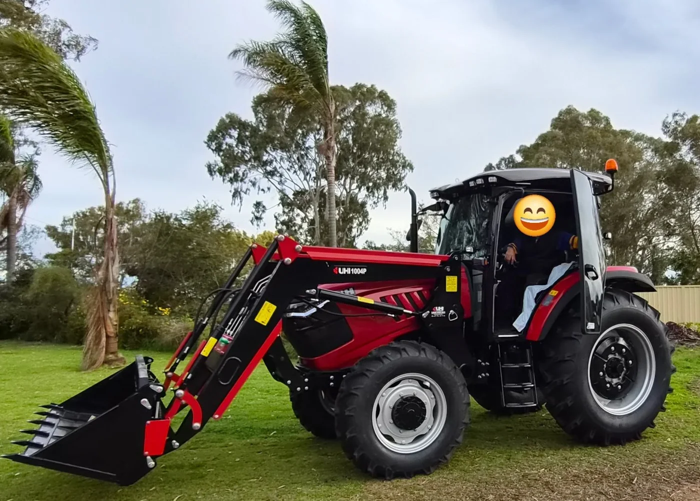 Red tractor with front-end loader on a grassy property.