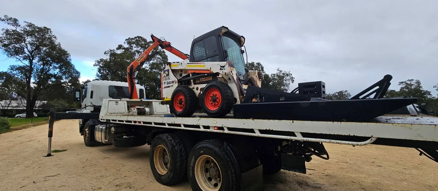 Bobcat skid steer loaded on a hiab truck with crane stowed.